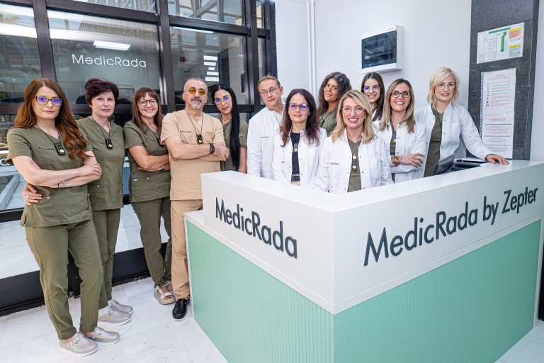 Grupna fotografija iskusnog tima lekara i osoblja klinike Medicrad ispred recepcije.
