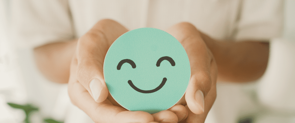 Baner za Psihologiju, ruke drže zeleni krug sa nasmejanim licem koji simbolizuje mentalno blagostanje.